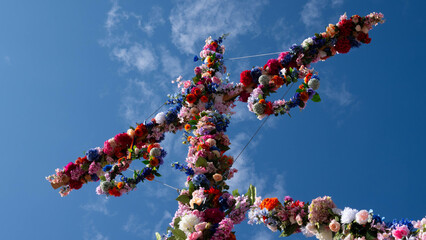 Colorful midsummer pole decorated with flowers against blue sky
