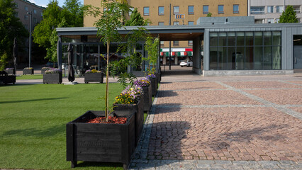 Modern urban square with potted plants and green lawn on a sunny day
