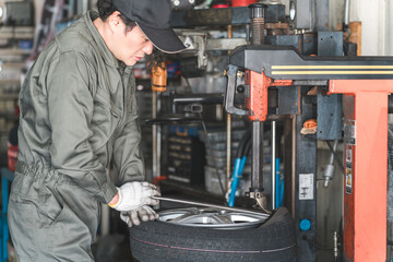 A male mechanic/service technician changes tires using a tire changer

