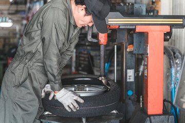 A male mechanic/service technician changes tires using a tire changer
