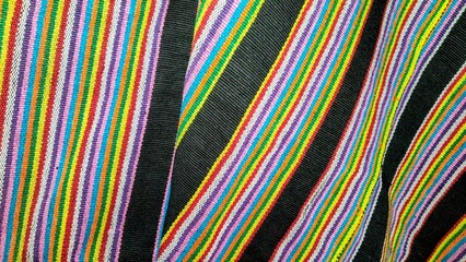 Vibrant diagonal stripes creating a dynamic and colorful abstract pattern on textured fabric,...