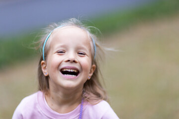 Smiling young girl wearing a pink sweatshirt and blue headband outdoors