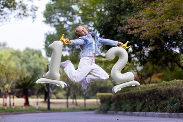 Young girl joyfully jumping with number balloons in a park