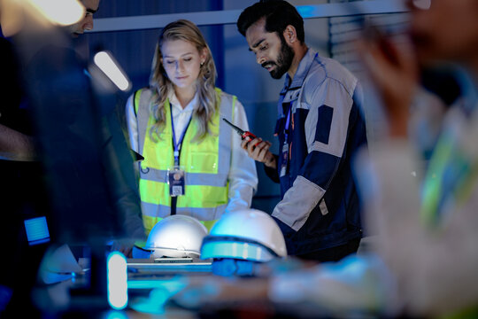 An Indian female technician in a safety vest monitors an AI-driven automation system. She is working in a smart factory command center, analyzing system data at night.