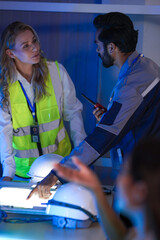 A diverse engineering team, a smiling Caucasian woman in a safety vest and an Indian man,...