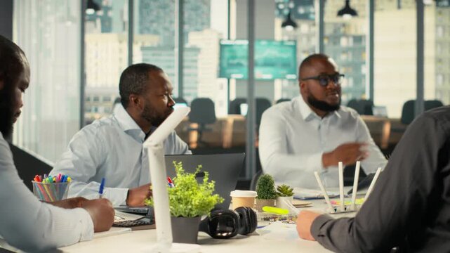 Colleagues and employees exchanging ideas during a business meeting. Professional team examines financial data, targets and business intel to align objectives for corporate progress. Camera B.