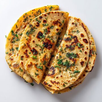 Golden brown folded flatbreads with fresh green herbs Stacked breads show charring arranged on a white background