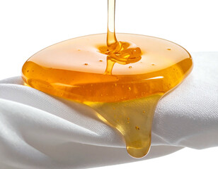 Viscous golden liquid pouring onto a textured white fabric creates a glossy, drippy effect