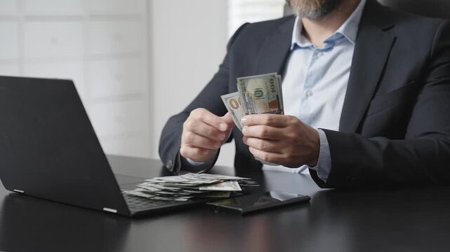 Businessman counting money at desk. Financial success and profit concept. Cash and online banking background. Man managing income and savings. Wealth and investment management scene.