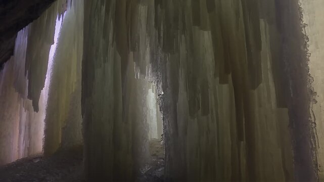 Thick vertical ice waterfall wall inside Eben Ice Caves, Michigan, USA. Tilt down view