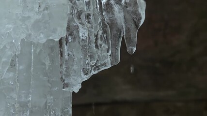 Crystal clear icicle hangs from a frozen cluster inside the Eben Ice Caves in Michigan, with water droplets forming at the tip. - Powered by Adobe