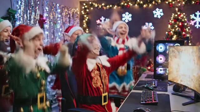 Christmas Elves Gaming - Three young gamers dressed as Christmas elves celebrate playing a video game. They are wearing elf costumes and santa hats while using computer with RGB peripherals.