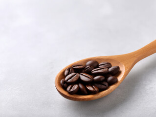 Fototapeta premium Roasted coffee bean in wooden spoon on light surface with warm natural tone and cozy feeling
