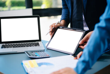 usiness professionals discussing financial report with data charts on tablet and laptop in modern office. Concept of analytics, teamwork