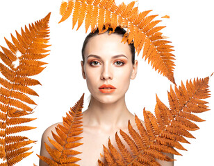 Woman framed by golden fern leaves; brown makeup and light skin, against a black background
