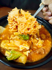 Close Up Shot of Spicy Indonesian Seblak Featuring Chewy Wet Kerupuk Being Lifted