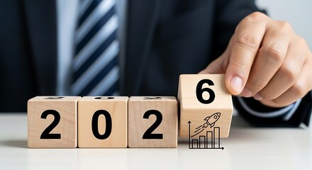 Businessman s hand turning wooden block from 2025 to 2026 symbolizing future growth and new year planning