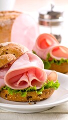 Close-up of sandwiches on a white plate with ham, lettuce, and bread