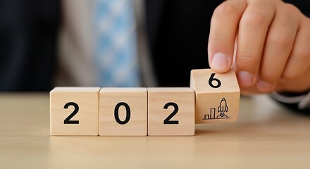 Hand turning wooden block from 2025 to 2026 symbolizing the transition to the new year and future planning