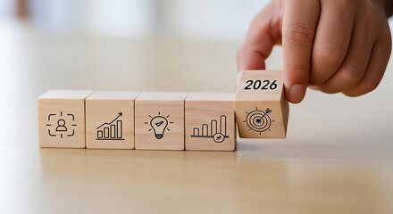 Hand placing wooden block with 2026 year on top of blocks with business icons symbolizing future growth and planning