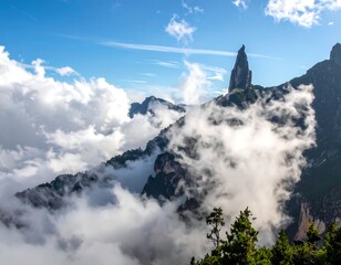Dramatic mountain peaks pierce fluffy clouds under a bright blue sky
