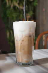 Iced coffee drink served in a tall glass with foam topping