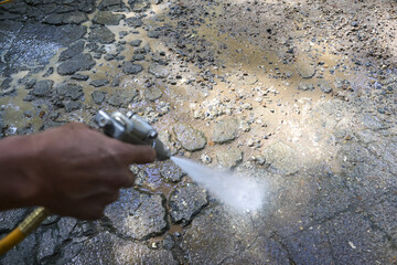 Worker hand holding spray gun painting rocky ground surface with white paint. focused action for an outdoor construction or repair job doing surface maintenance