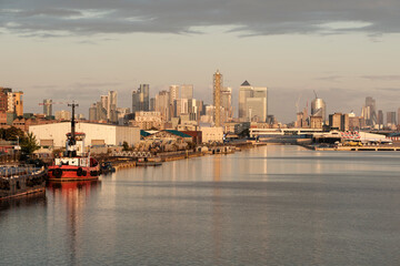 Fototapeta premium London canary wharf cityscape with tugboat on river thames at sunrise