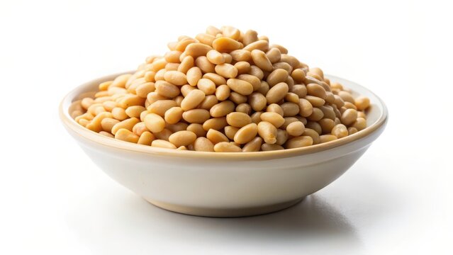 Small bowl of roasted pine nuts in a shallow dish on a plain white background