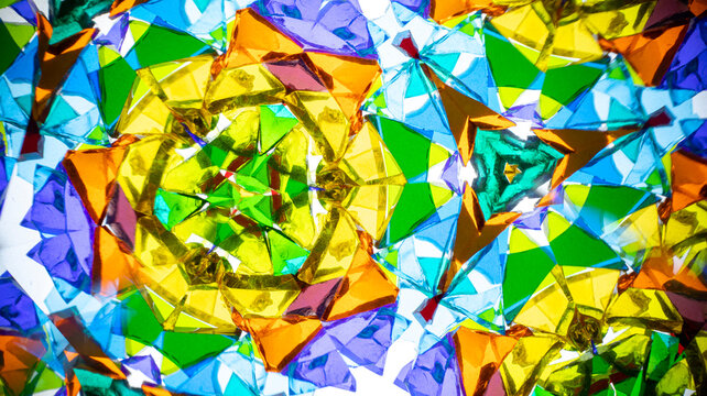 A vibrant macro photograph of an abstract, symmetrical, and colorful pattern captured through a kaleidoscope, showcasing rich geometric reflections.