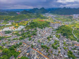 The pond with ships and streets of Qingyan Ancient Town, one of the top 4th famous old towns and popular travel destination in Guizhou Province, China, aerial drone shot