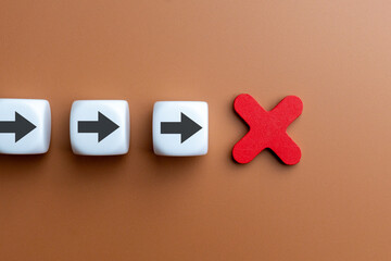 A single red X sign interrupts a line of white dice with black arrows. Mistake, cancellation, failure, wrong direction, or the stopping of an action or plan concept.