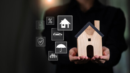 A person holds a wooden house model with floating icons representing insurance categories like home, family, car, and umbrella, visualizing modern protection and digital policy solutions.