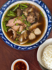 The closed up of Thai noodles. Asian noodle soup with beef meatball with fresh vegetable on wood table.