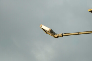 Streetlight against a cloudy sky, close-up view.