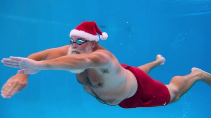Santa Claus swimming freestyle in a pool. A unique Christmas sports concept for health, endurance, and holiday fitness themes.