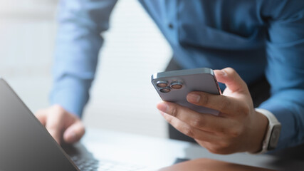 using, smartphone, social media, internet, A person using smartphone while working on laptop, representing digital lifestyle, social media use, online communication, and mobile technology connection.