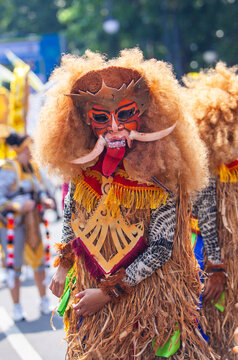 Vibrant Indonesian folk performance art. A participant from Sleman wears an elaborate mask and costume representing a mythical creature during Bandung's Asia Africa Carnival.