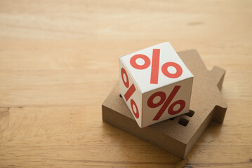 Percentage sign on house wooden table background. Burden from high interest rate mortgage loan, Fed central bank control interest rate, profit or yield from real estate investment trust (REIT) concept