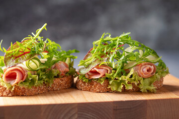 Sandwich with lettuce, cucumber, ham and cheese on the table. School or office snack