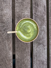 A vibrant, fresh green smoothie beautifully swirled in a bowl, elegantly presented atop a rustic wooden table