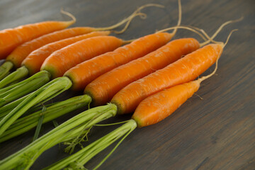 Fresh Orange Carrots with Green Tops on Wooden Surface