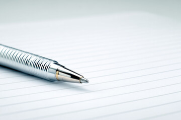 Silver pen metal pen ballpoint pen writing instrument lined paper office supply stationery closeup diagonal minimal clean modern reflection shiny smooth horizontal blank document business