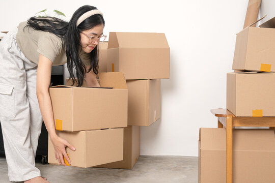 young woman lifting cardboard boxes when moving to a new house