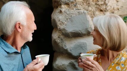 Healthy centenarians smiling elderly couple and happy senior woman and man enjoying tea drink together outdoors sharing peaceful