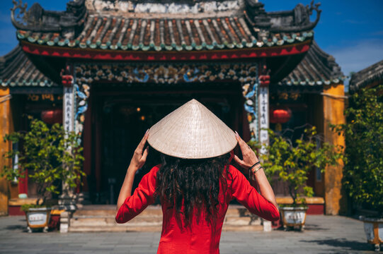 A woman in a traditional Vietnamese dress on the background of the temple of Asian culture in Hoi An