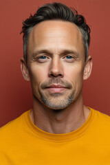 Obraz premium a handsome 40-year-old blond man. He wears a bright yellow t-shirt against a plain light red background