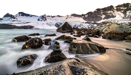 Snowy mountain backdrop with rocky beach and blurred ocean waves