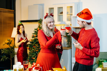 Group of cheerful friends enjoying Christmas celebration with gifts, food, and holiday decorations in a warm festive atmosphere.