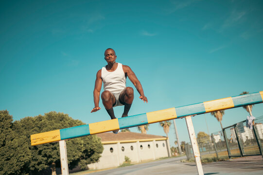 Athlete man jumping barrier training for fitness outdoors - Powered by Adobe